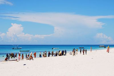 People on sea shore against sky at zanzibar beach