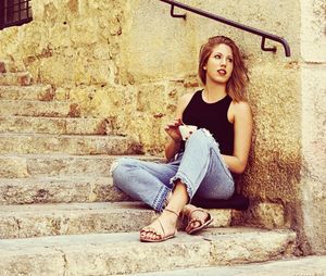 Full length of young woman sitting on staircase