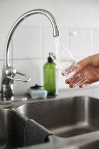 Hand pouring tap water into glass