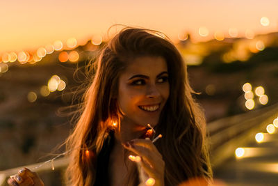 Close-up portrait of smiling young woman in city at night