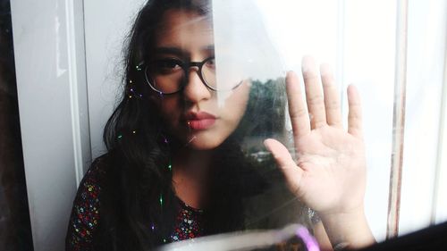Portrait of young woman looking through window