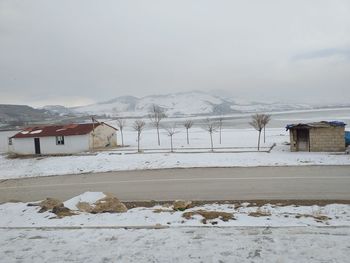 Snow covered houses by buildings against sky