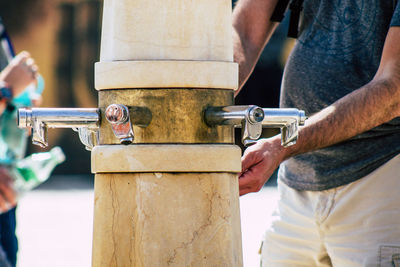 Midsection of man filling water from faucet