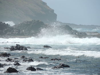 Waves splashing on sea against sky