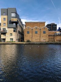 Canal by building against sky