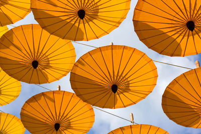 Low angle view of orange umbrellas against sky