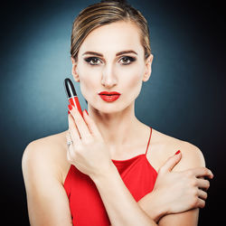 Portrait of female model holding beauty product against colored background