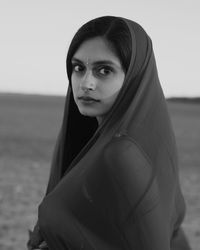 Portrait of young woman wearing dupatta on field against sky
