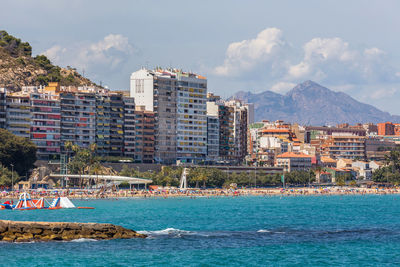 Buildings at waterfront against cloudy sky