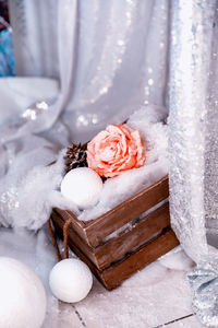 Coral rose covered with artificial snow, against the background of a curtain of silver sequins