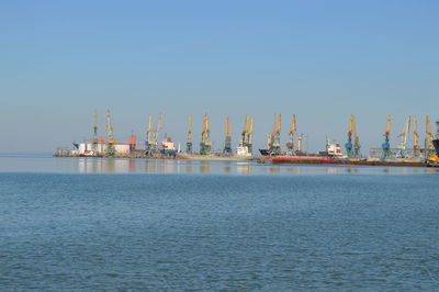 Commercial dock by sea against clear blue sky