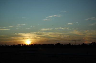 Scenic view of silhouette field against sky at sunset