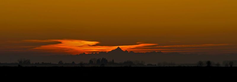 Silhouette of temple against orange sky