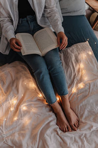 Low section of woman relaxing on bed