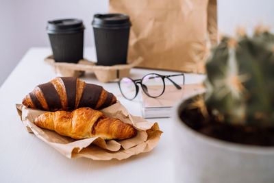 Delicious brown and chocolate croissants with coffee cups, having lunch at workplace, food delivery