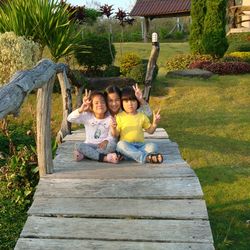 Portrait of siblings sitting on footbridge at park