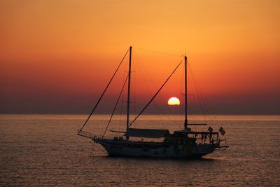 Sailboat in sea against orange sky