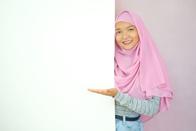 Portrait of smiling woman standing against pink wall