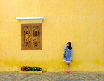 Full length of woman standing by wall