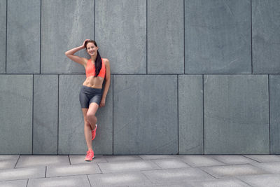 Woman in sports clothing standing against wall