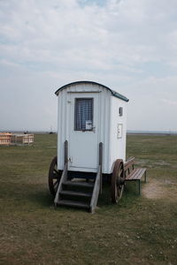 Portable toilet on grassy field against sky