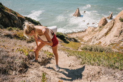 High angle view of young woman standing on mountain against sea