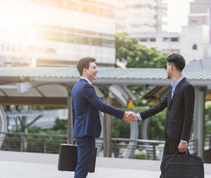Young businessman shaking hands with colleague in city