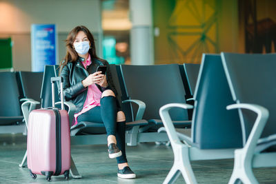 Full length of woman wearing mask sitting on chair