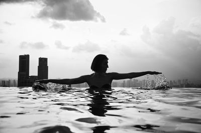 Woman in swimming pool in city against sky