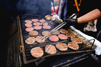 Midsection of man preparing meat on barbecue grill