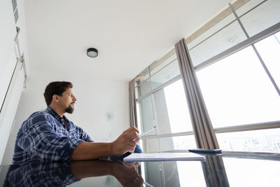 Young man working at home signing papers smiling 