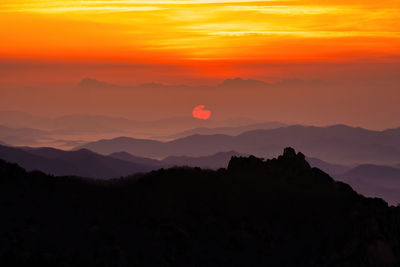 Scenic view of silhouette mountains against orange sky during sunset