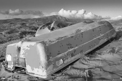 Damaged car on snow covered land against sky