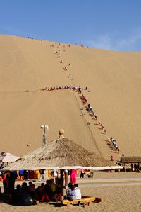 High angle view of people on sand dune against clear sky