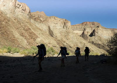 People on sand dune against clear sky