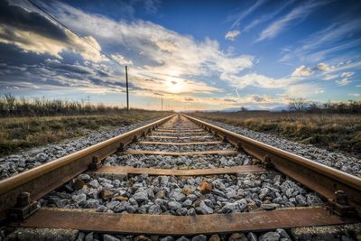 Railroad tracks against sky during sunset