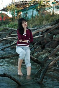 Portrait of smiling young woman standing against trees