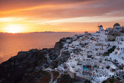 Aerial view of townscape by sea against sky during sunset