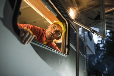 Low angle view of man looking through window of motor home