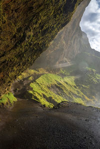 View of scenic seljalandsfoss with mist on mountain against cloudy sky