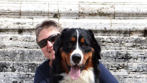 Portrait of woman with dog against wall