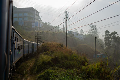 Electricity pylons by mountain against sky