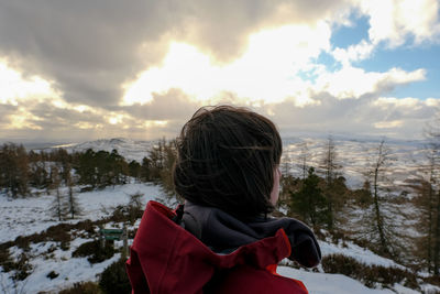 Rear view of woman standing on snow against sky