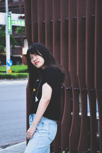 Portrait of young woman standing against wall