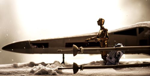 Figurine by toy airplane on snow covered field