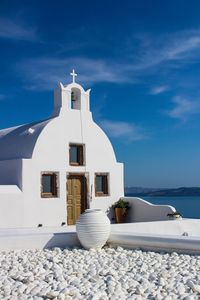 White building by sea against blue sky