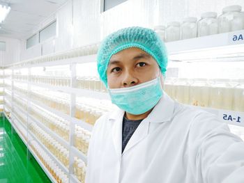 Portrait of scientist standing against shelf in laboratory