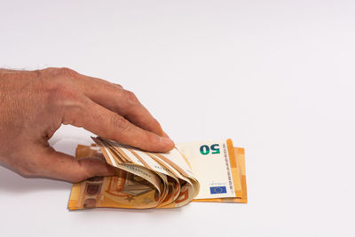 Close-up of hand holding paper over white background