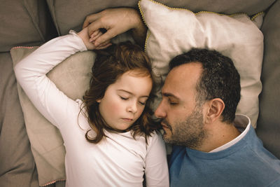 Directly above shot of father and daughter sleeping on couch at home