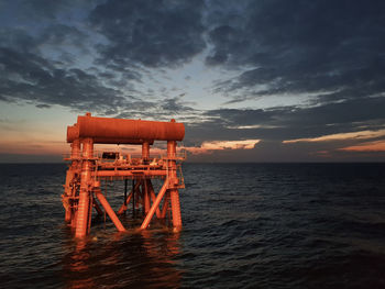 Lifeguard hut on sea against sky during sunset
